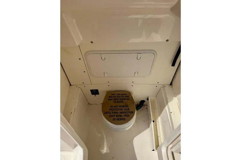 Slide: The Image of 2022 Robalo 266 Cayman interior storage compartment with protective film instructions. - 7