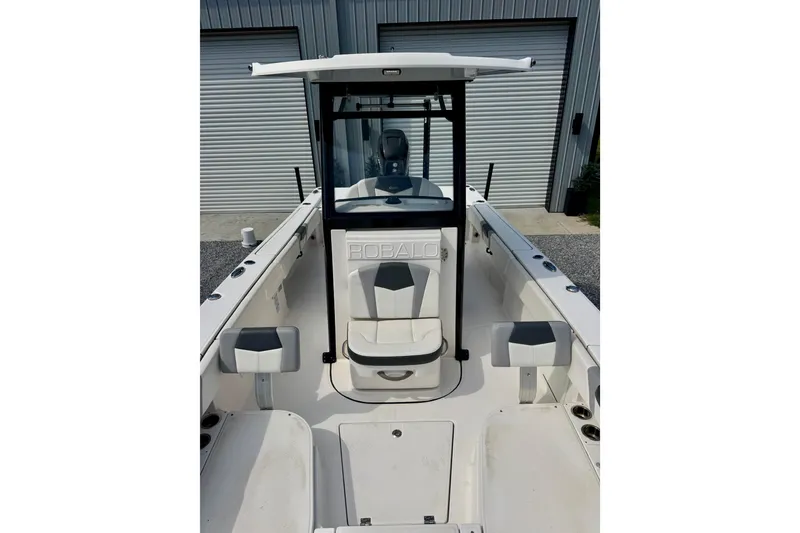Slide: The Image of 2022 Robalo 266 Cayman boat interior with seating and console, parked near garage doors. - 8