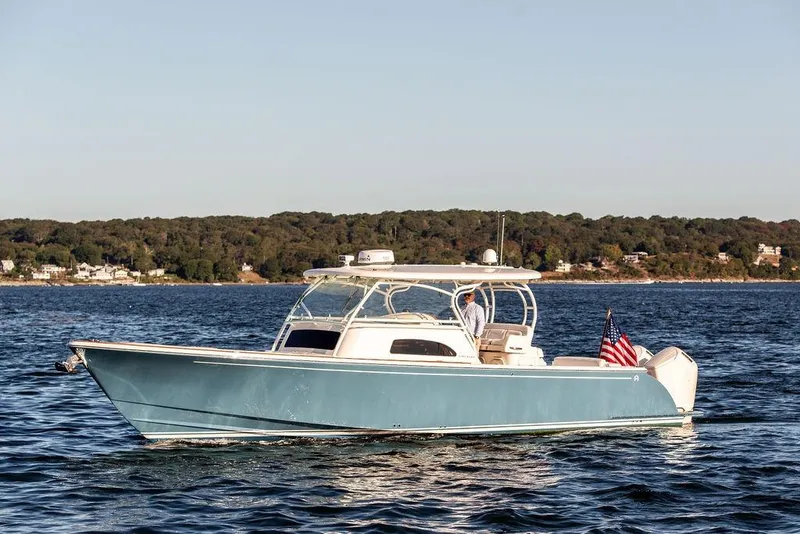 The Image of 2024 Hinckley Sport Boat 40c cruising on a serene lake with forested shoreline. - 0