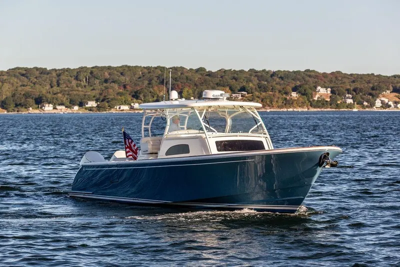 Slide: The Image of 2024 Hinckley Sport Boat 40c cruising on a scenic lake with forested shoreline. - 1