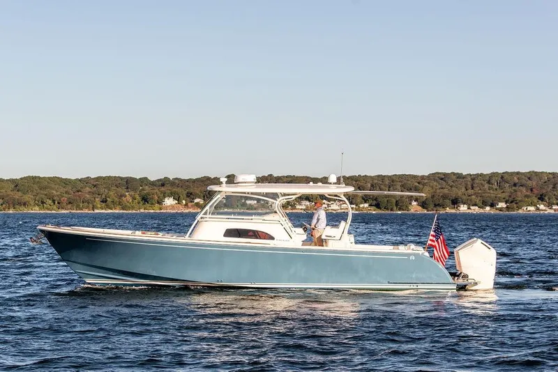 Slide: The Image of 2024 Hinckley Sport Boat 40c cruising on a serene lake with American flag. - 39