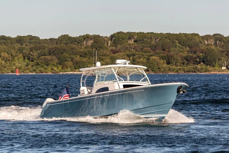 Slide: The Image of 2024 Hinckley Sport Boat 40c cruising on a scenic lake with forested background. - 40