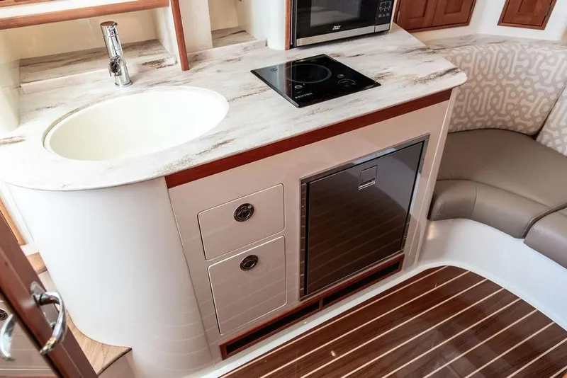 Slide: The Image of 2024 Hinckley Sport Boat 40c interior with kitchenette, featuring sink, stove, and seating area. - 29