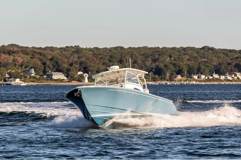 Slide: The Image of 2024 Hinckley Sport Boat 40c cruising on a serene lake with forested shoreline. - 3