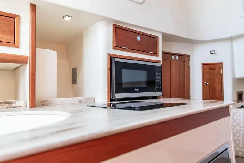 Slide: The Image of 2024 Hinckley Sport Boat 40c interior with modern kitchen appliances and wooden cabinetry. - 34