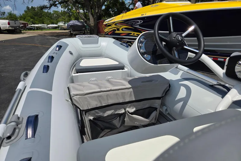 Slide: The Image of 2025 Highfield Classic 360 boat interior with steering wheel and seating, parked outdoors. - 13