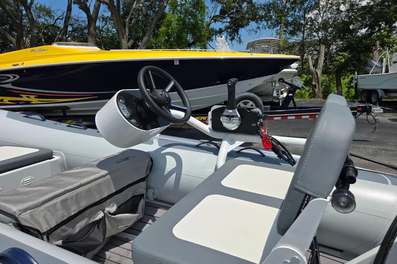 Slide: The Image of 2025 Highfield Classic 360 boat interior with steering wheel and seating, parked near a yellow speedboat. - 14