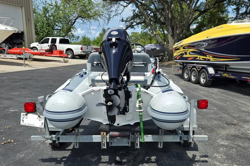 Slide: The Image of 2025 Highfield Classic 360 inflatable boat on trailer, parked near other boats. - 4