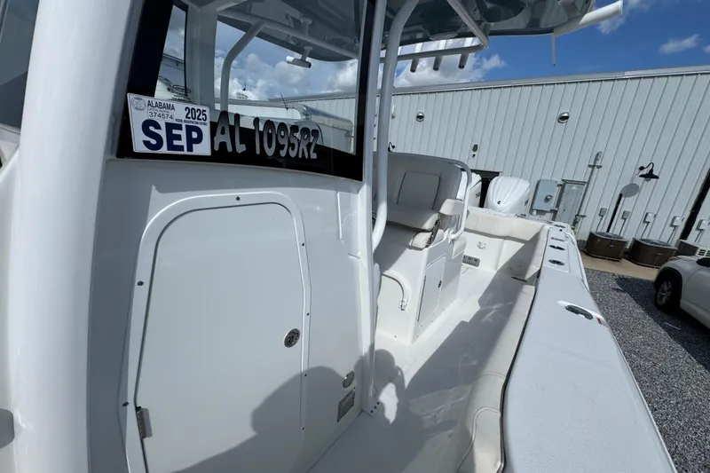 Slide: The Image of 2023 Sea Hunt Gamefish 30 Coffin Box boat, white interior, docked near a metal building. - 23