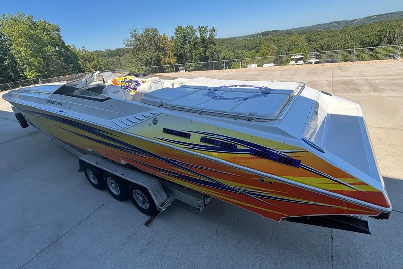 Slide: The Image of 2006 Fountain 42 Executioner speedboat with vibrant graphics on a trailer, surrounded by trees. - 6