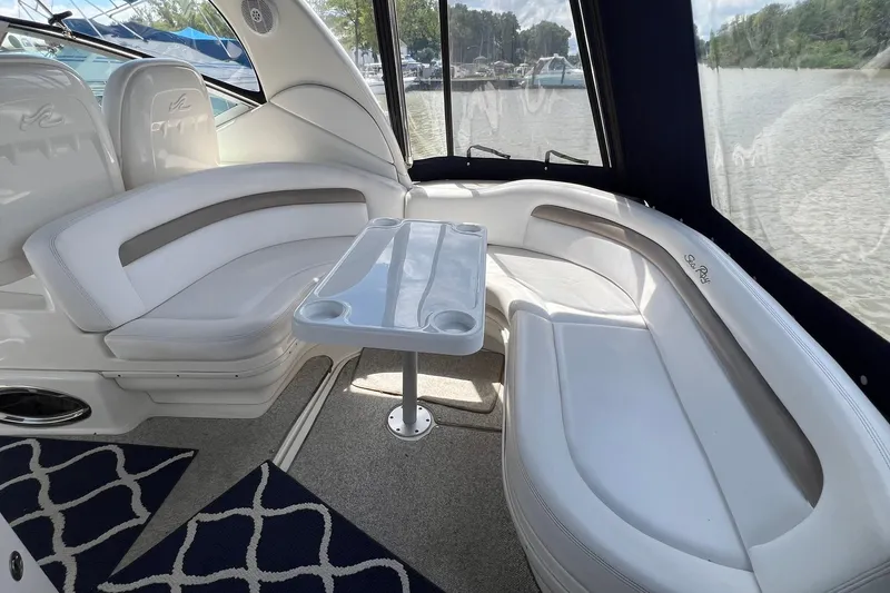 Slide: The Image of 2005 Sea Ray 340 Sundancer interior with white seating and table, docked by the water. - 3