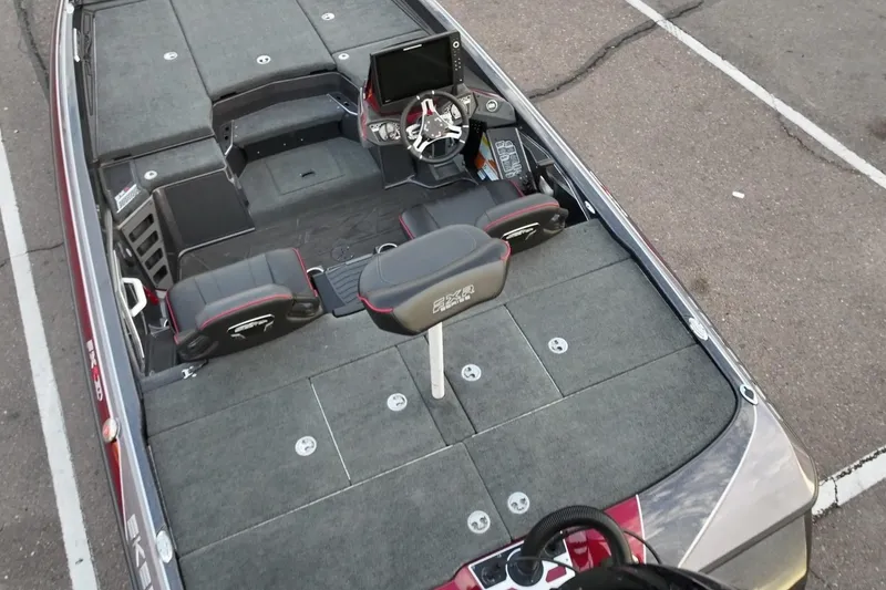 Slide: The Image of 2023 Skeeter FXR21 boat interior with seating and control panel, parked on asphalt. - 14