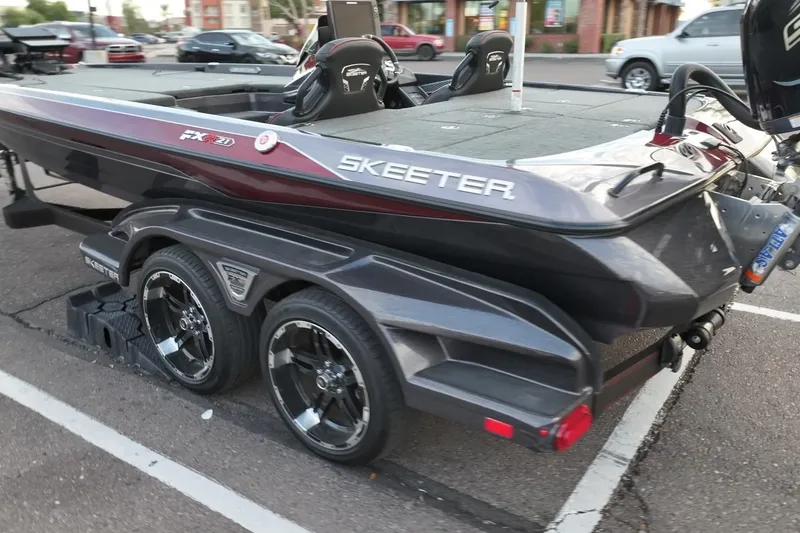 Slide: The Image of 2023 Skeeter FXR21 boat on trailer in parking lot, showcasing sleek design and dual wheels. - 3
