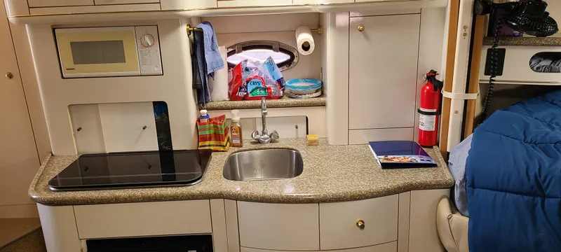 Slide: The Image of 1998 Maxum 3000 SCR boat kitchen with sink, stove, microwave, and fire extinguisher. - 14