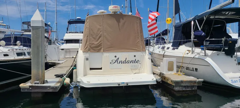 Slide: The Image of 1998 Maxum 3000 SCR boat docked at marina, covered, with American flag. - 2