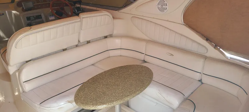 Slide: The Image of 1998 Maxum 3000 SCR boat interior with white leather seating and a round table. - 3