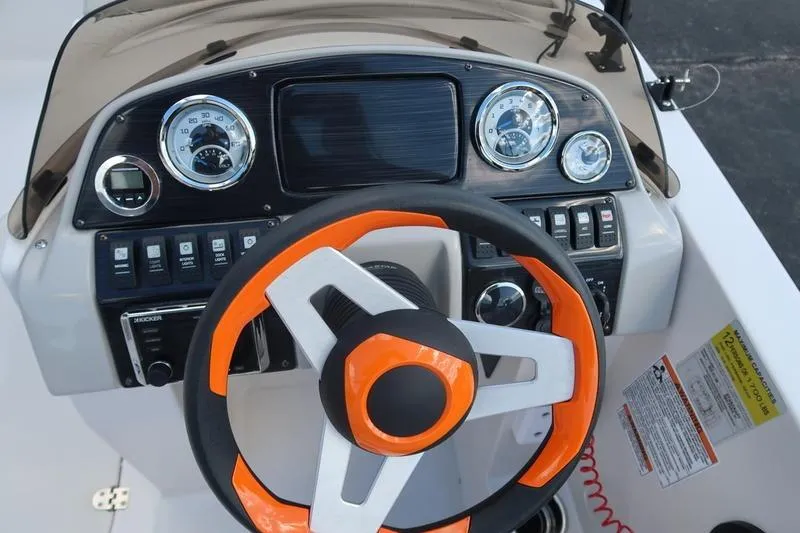 Slide: The Image of 2020 Starcraft MDX OB 211 E OB boat dashboard with orange-accented steering wheel and gauges. - 14