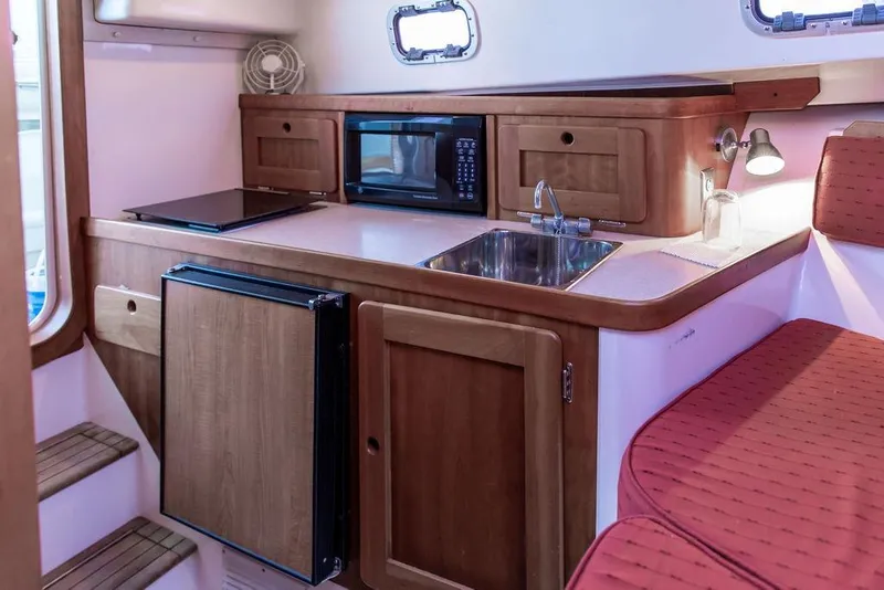 Slide: The Image of 2008 Hunt Yachts Surfhunter 29 interior with kitchenette, featuring sink, microwave, and seating. - 16