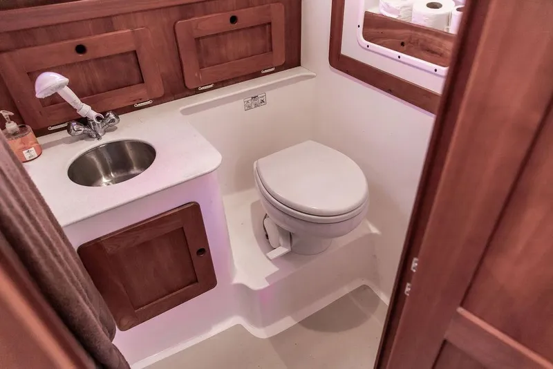 Slide: The Image of 2008 Hunt Yachts Surfhunter 29 bathroom with sink, toilet, and wooden cabinetry. - 18