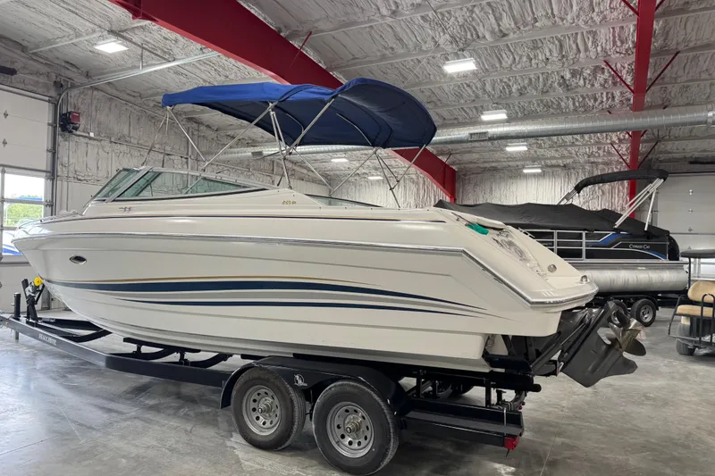 Slide: The Image of 1999 Formula 280 Bowrider boat with blue canopy on trailer in indoor storage. - 4