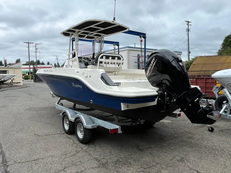 Slide: The Image of 2021 Bayliner Trophy boat on trailer with Mercury outboard motor, parked outdoors. - 17