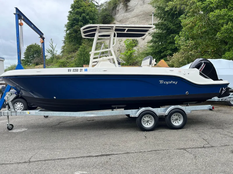 Slide: The Image of 2021 Bayliner Trophy boat on trailer, blue hull, parked outdoors. - 2