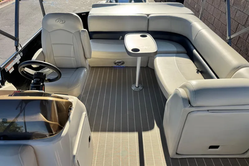 Slide: The Image of 2021 Manitou 23 Aurora LE Standard boat interior with seating and steering wheel. - 16
