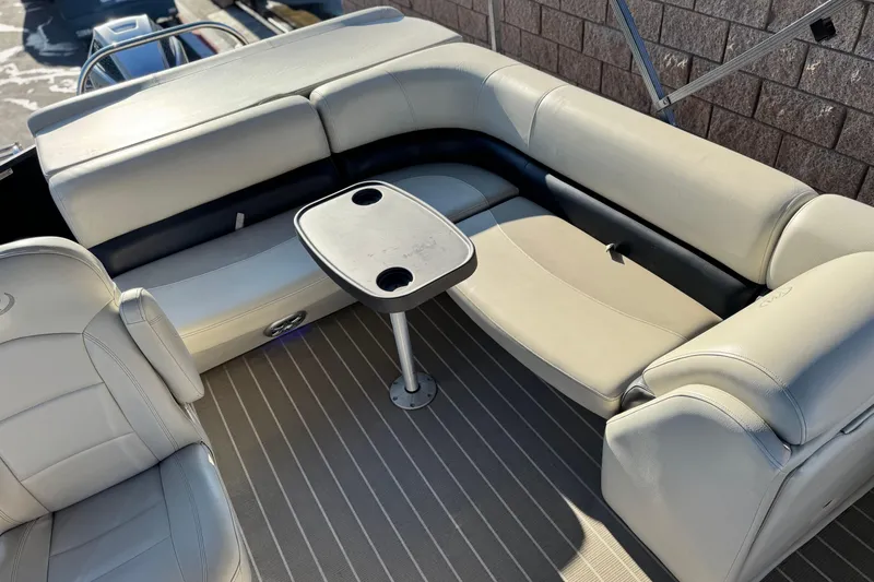 Slide: The Image of 2021 Manitou 23 Aurora LE Standard boat interior with beige seating and a small table. - 17