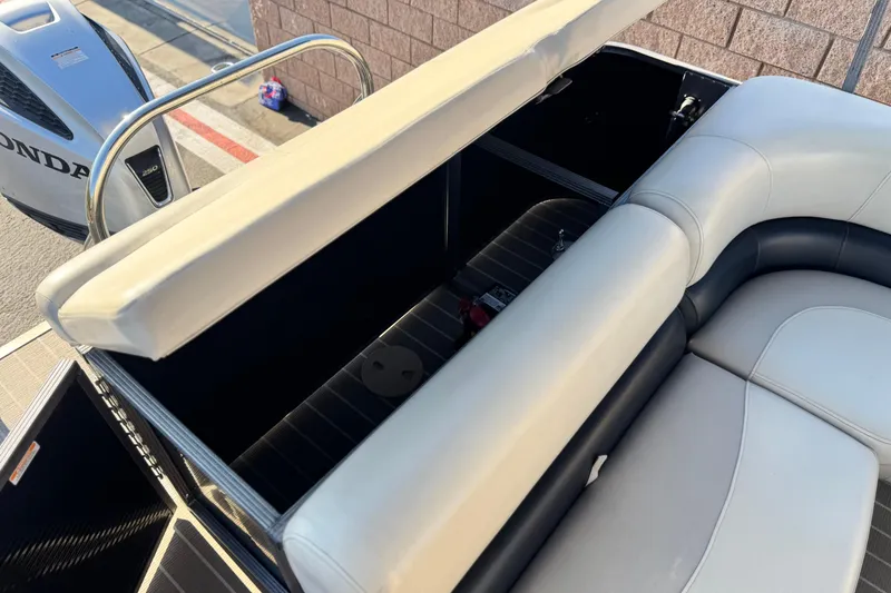 Slide: The Image of 2021 Manitou 23 Aurora LE Standard boat with open storage compartment and Honda engine. - 19