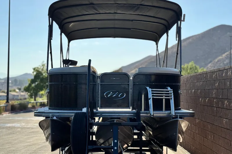 Slide: The Image of 2021 Manitou 23 Aurora LE Standard pontoon boat with canopy, parked outdoors. - 2