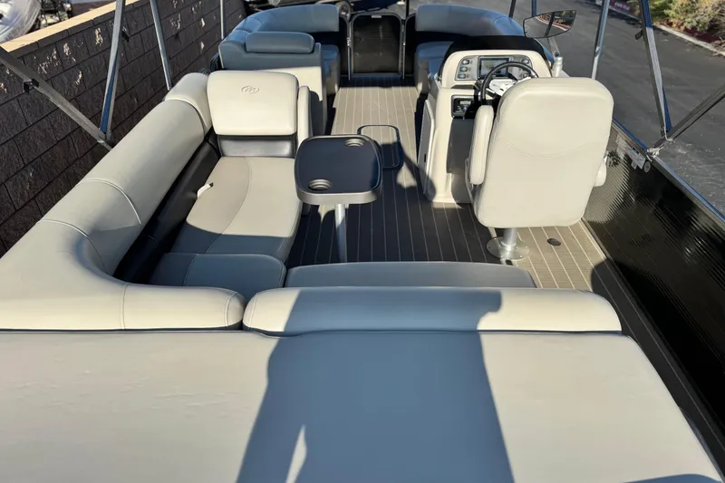 Slide: The Image of 2021 Manitou 23 Aurora LE Standard pontoon boat interior with plush seating and steering console. - 20