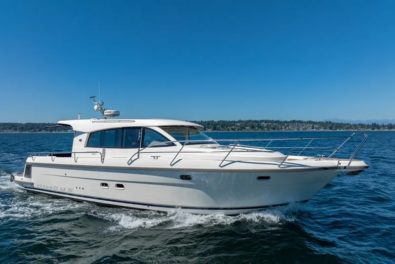 Slide: The Image of 2022 Nimbus 405 Coupé yacht cruising on open water under clear blue skies. - 2