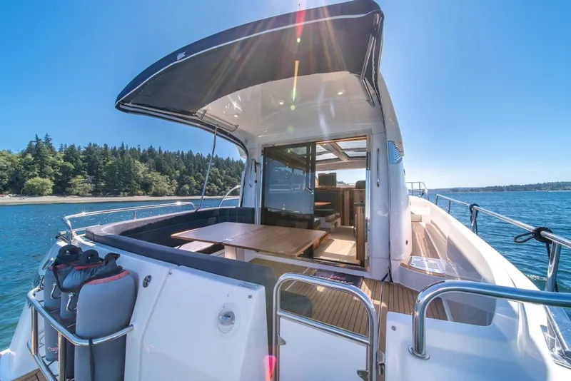 Slide: The Image of 2022 Nimbus 405 Coupé yacht with open deck, scenic water view, and lush forest backdrop. - 39