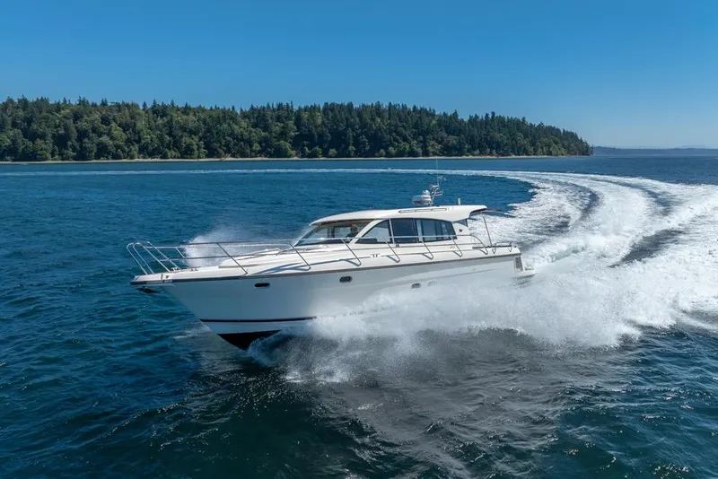 Slide: The Image of Nimbus 405 Coupé 2022 cruising on open water with forested shoreline in background. - 53