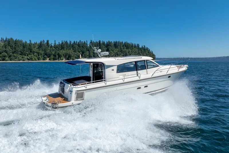 Slide: The Image of 2022 Nimbus 405 Coupé cruising on open water, surrounded by lush forest. - 7