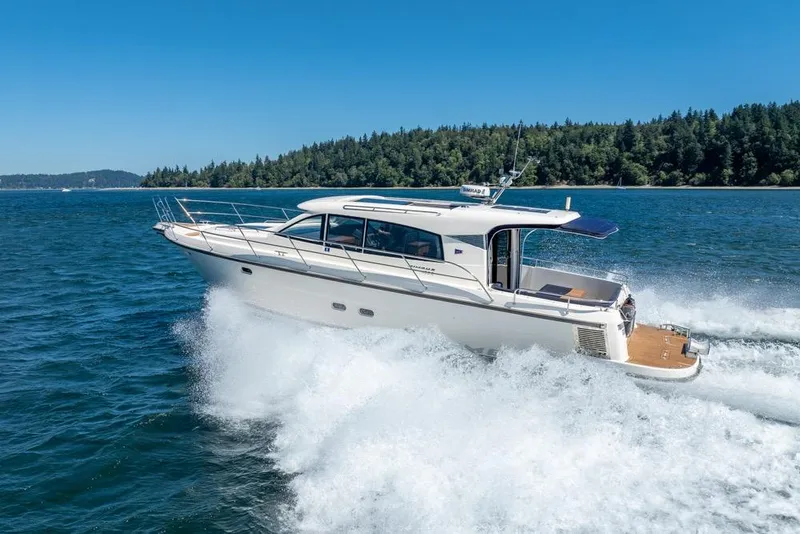 Slide: The Image of 2022 Nimbus 405 Coupé cruising on a scenic lake with forested shoreline. - 8