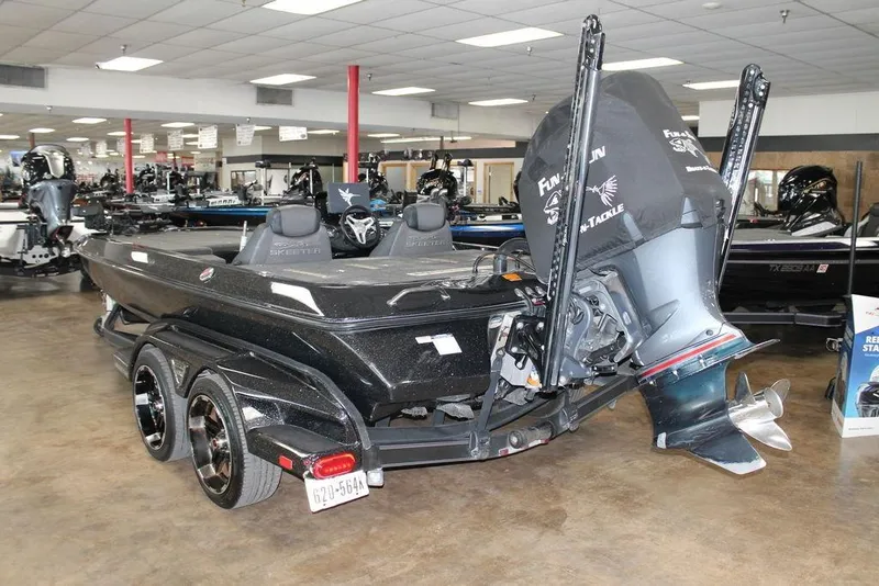 Slide: The Image of 2019 Skeeter FX21 LE boat in showroom, featuring dual axle trailer and powerful outboard motor. - 1