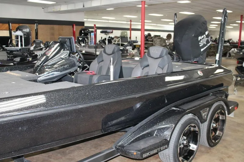 Slide: The Image of 2019 Skeeter FX21 LE bass boat in showroom, featuring sleek black design and modern seating. - 5