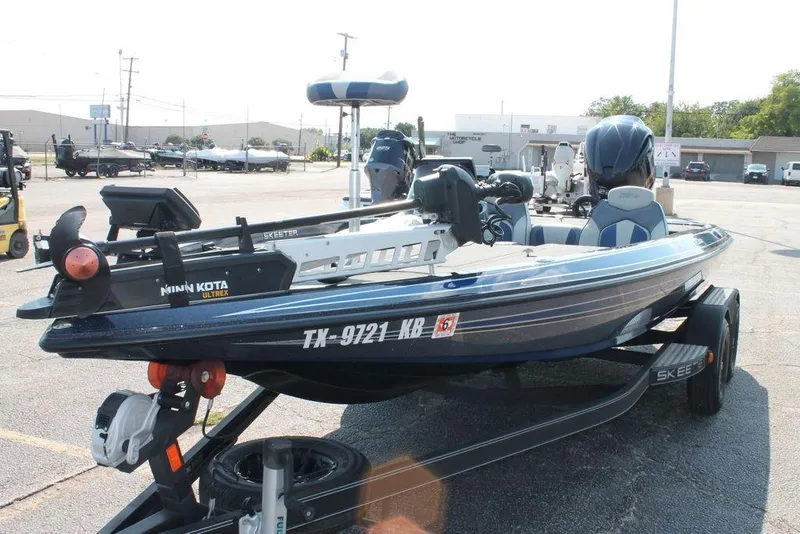 Slide: The Image of 2021 Skeeter ZX225 bass boat with Minn Kota Ultrex trolling motor in parking lot. - 1