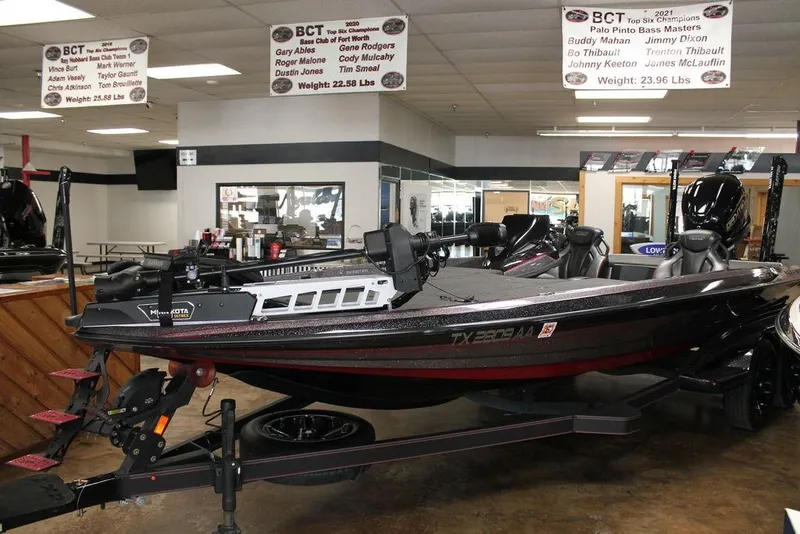 Slide: The Image of 2025 Skeeter FXR21L bass boat displayed indoors with fishing equipment. - 3