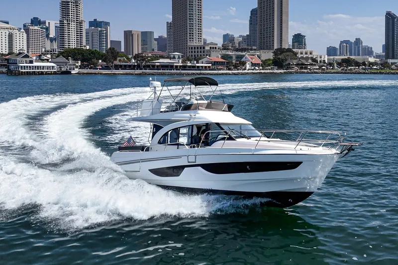 Slide: The Image of 2023 Beneteau Antares 11 Fly cruising near city skyline, creating dynamic water trail. - 5