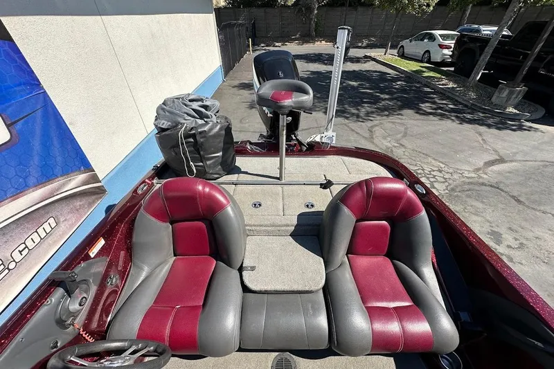 Slide: The Image of 2010 Ranger 178 VS boat interior with red and gray seats, parked outdoors. - 13