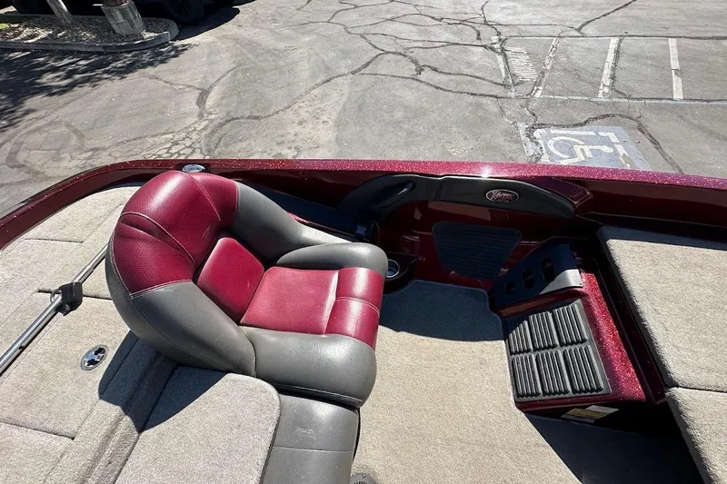 Slide: The Image of 2010 Ranger 178 VS boat interior with red and gray seating, parked on cracked pavement. - 18