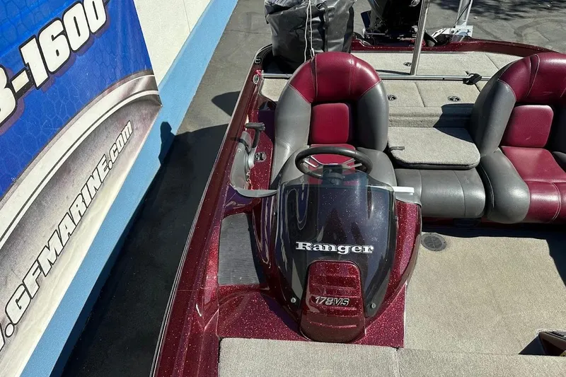 Slide: The Image of 2010 Ranger 178 VS boat interior with red and gray seating, steering console, and branding. - 27