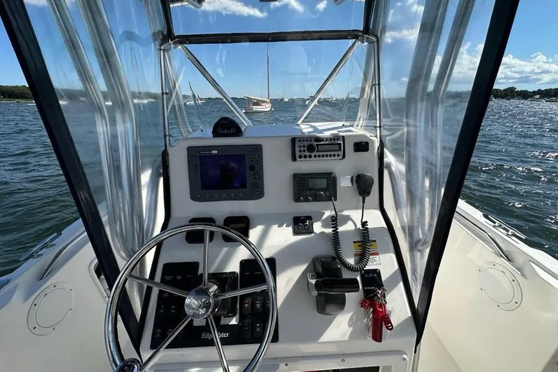 Slide: The Image of 2007 Edgewater 245CC boat cockpit with steering wheel and navigation equipment on open water. - 2