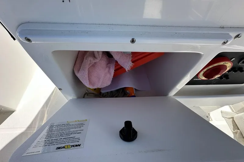 Slide: The Image of Storage compartment on a 2007 Edgewater 245CC boat with safety equipment and Sea Tow information. - 25