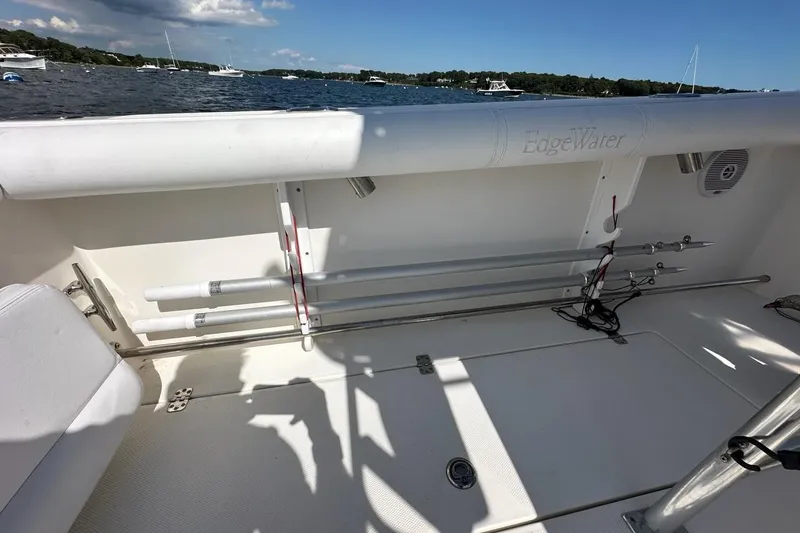 Slide: The Image of 2007 Edgewater 245CC boat interior with rod holders and seating, docked on a sunny day. - 29
