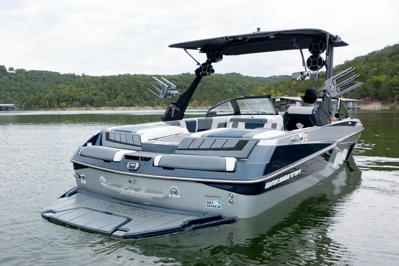Slide: The Image of 2021 Malibu Wakesetter 23 MXZ boat on a serene lake with lush green hills. - 3