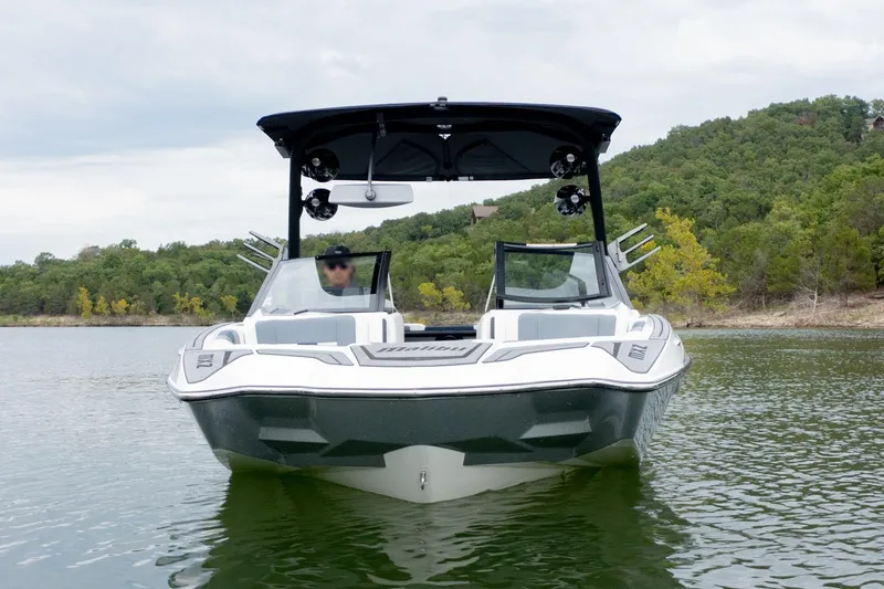 Slide: The Image of 2021 Malibu Wakesetter 23 MXZ boat on a scenic lake with lush green hills. - 4