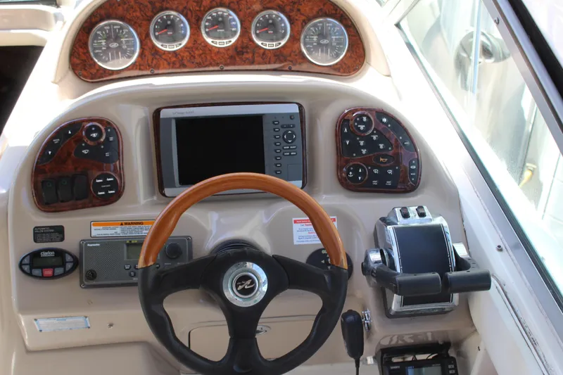 Slide: The Image of 2005 Sea Ray 300 Sundancer helm with gauges, controls, and wood-trimmed steering wheel. - 13
